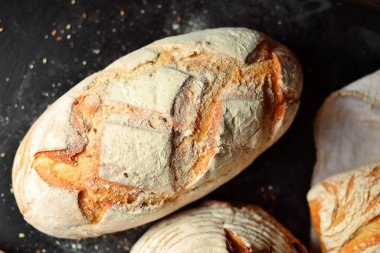 Fırın ürünleri. Koyu arka planda çıtır çıtır, güzel bir ekmek. Karabuğday, mayasız, keten ve ayçiçeği tohumlu buğday ekmeği. Üst görünüm, metin için yer.