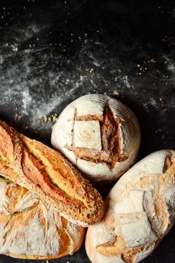 Fırın ürünleri. Koyu arka planda çıtır çıtır, güzel bir ekmek. Karabuğday, mayasız, keten ve ayçiçeği tohumlu buğday ekmeği. Üst görünüm, metin için yer.