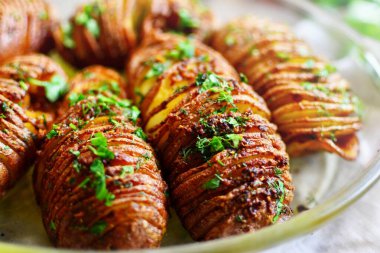 Fırında pişirilmiş iştah açıcı patates akordeonu. Tahta arka planda patates. Hasselback patatesleri. Vejetaryen yemeği, maydanozlu sebze ve sarımsaklı