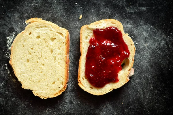 Sandwich with raspberry jam. Sandwich on a dark background isolated. Delicious raspberry and strawberry jam. Place for text. Top view, a slice of white bread, a slice of bread with jam.