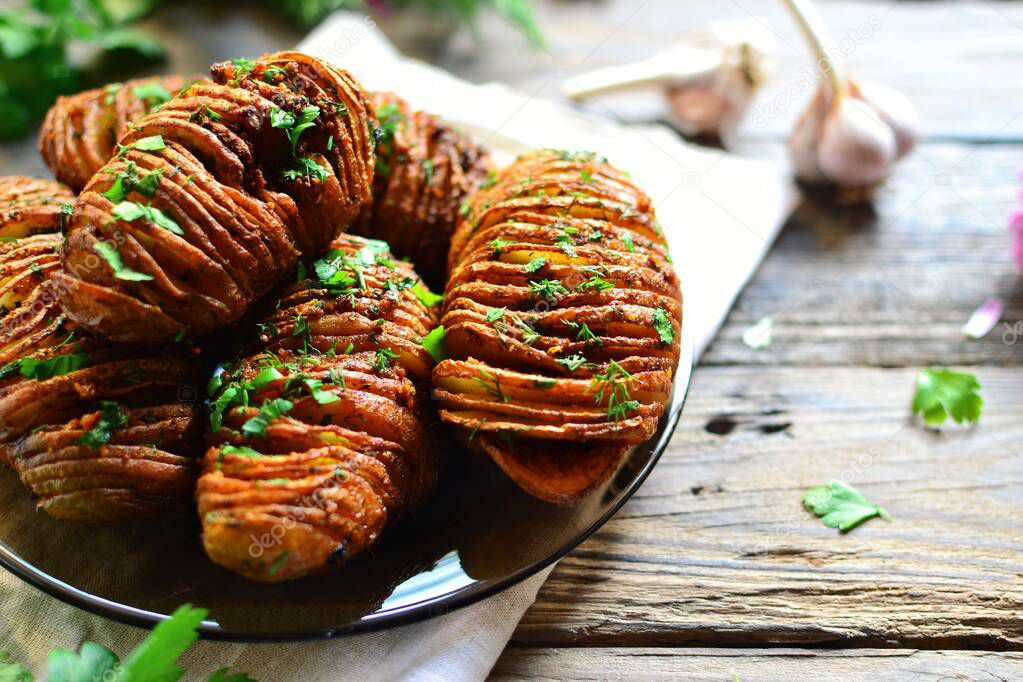 Appetizing potato accordion baked in the oven. Potato on a wooden background. Hasselback potatoes. Vegan food, vegetables with parsley and garlic