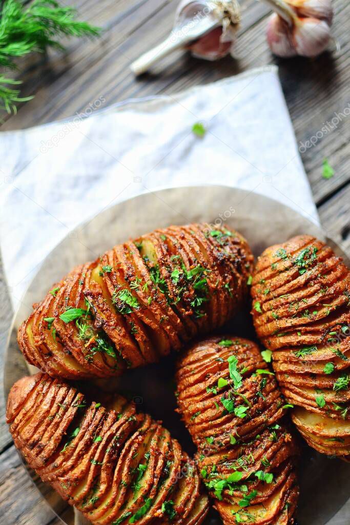 Hasselback potatoes. Appetizing potato accordion baked in the oven. Potato on a wooden background. Top view