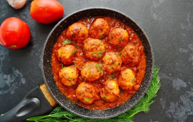 Domates soslu tavuk köftesi iştah açıcı. Köfteler arka planda bir tencerede. Domatesli tavuk pirzolası. Metin için boş alan.