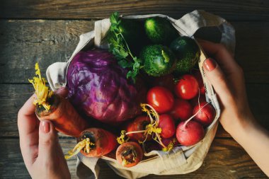 Turp, domates, salatalık, havuç, kırmızı lahana. Ahşap arka. Üst Manzara. Ellerini çerçeveye koy. Kadının elinde sebze var..