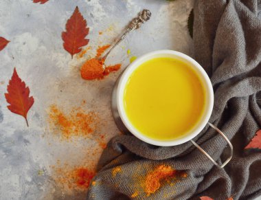 Beyaz bardakta altın süt. Sonbahar yaprakları. Süt, zerdeçal, tarçın ve baldan yapılmış sağlıklı bir içecek. Sarı süt