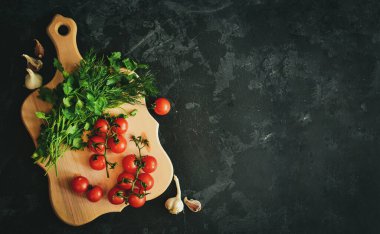 Salata için taze sağlıklı sebzeler. Kirazlı domates ve maydanoz, dereotlu. Kesme tahtasındaki domatesler. Karanlık arka plan. Metin için boş alan. Üst Manzara. Çiğ yemek.