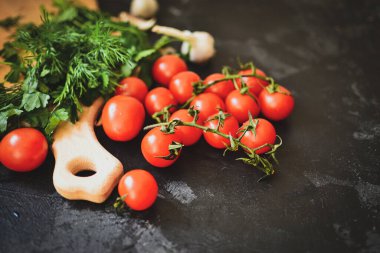 Salata için taze sağlıklı sebzeler. Kirazlı domates ve maydanoz, dereotlu. Kesme tahtası. Karanlık arka plan. Metin için boş alan. Yiyecek.