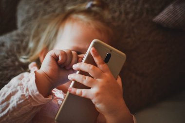 Güzel küçük kız akıllı telefondan çizgi film izliyor. Video iletişimi. Çevrimiçi arkadaşlara çağrı. Arkadaşların mesafesi. Çocuklara çevrimiçi öğretmenlik. Bir çocuk akıllı telefondan oynar. Evde vakit geçirmek.