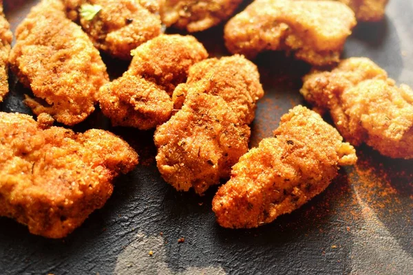 Fried crispy chicken nuggets on a dark background. Tasty fried chicken meat isolated. Free Place for text.
