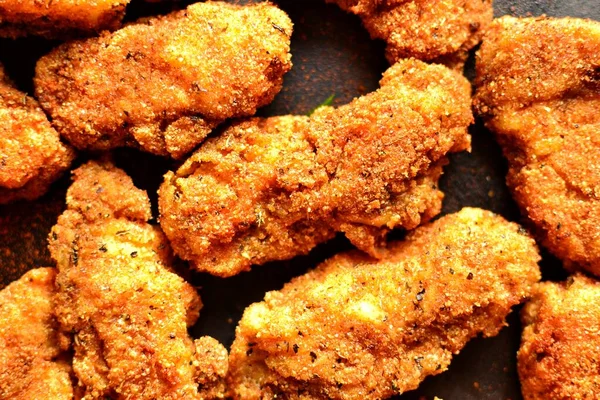 Fried crispy chicken nuggets on a dark background. Tasty fried chicken meat isolated. Place for text.