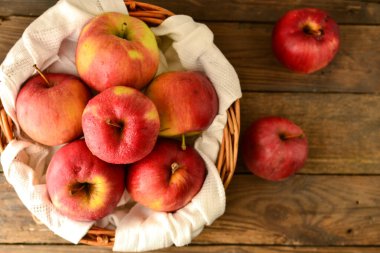 Sepette kırmızı elmalar. Tahta bir arka planda hasır bir sepette olgun elmalar, üst manzara..