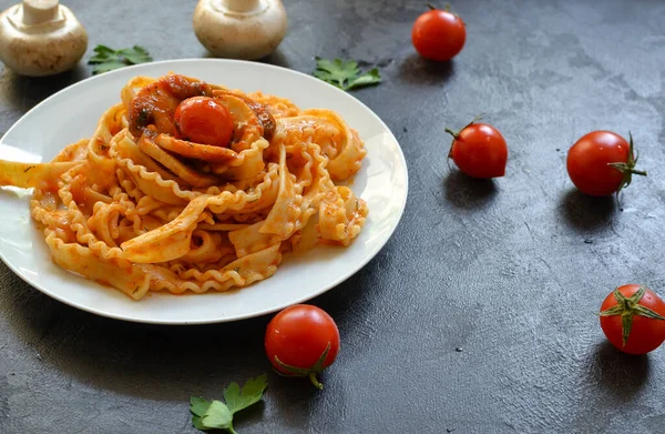 白盘里的意大利面 番茄酱意大利面 樱桃西红柿蘑菇 黑暗的背景自由的文字空间 好吃的食物 — 图库照片