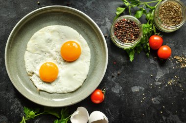 Tabakta pişmiş yumurta. Güzel yağda yumurta. Lezzetli bir kahvaltı. Üst manzara, koyu beton arkaplan.