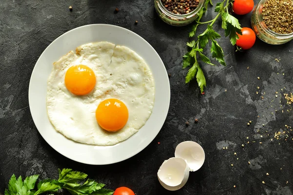 Tabakta pişmiş yumurta. Güzel yağda yumurta. Lezzetli bir kahvaltı. Üst manzara, koyu beton arkaplan.
