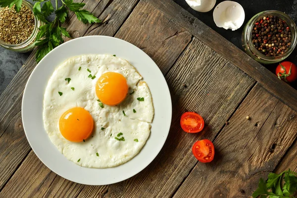 Tasty fried eggs for breakfast. Fried eggs in a plate on a wooden table background, top view.