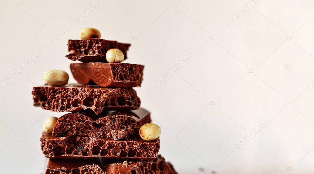 Chocolate on a white background, isolated. Porous chocolate with nuts, texture, close-up