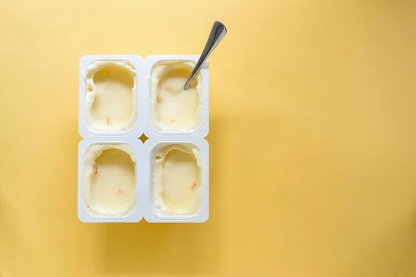 The food is minimal in style. Minimal food concept. Yogurt in a cup. Yogurt on a yellow pastel background. Top view. A free place for text. Healthy breakfast and snack foods.