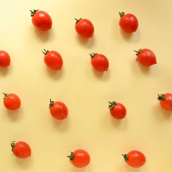 The food is minimal in style. Minimal food concept. Tomatoes on a yellow pastel background. Tomatoes pattern. Top view.