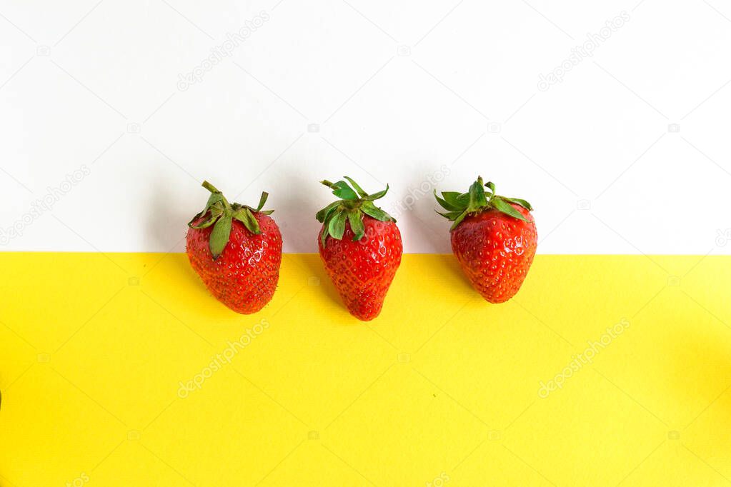 Minimal food concept. Strawberries on a yellow and white background. Top view. Free space for text. Tasty berries. Pattern