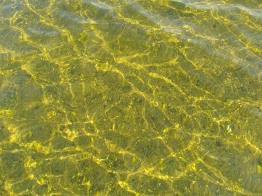 Gölün kumlu tabanında güneş parlıyor..