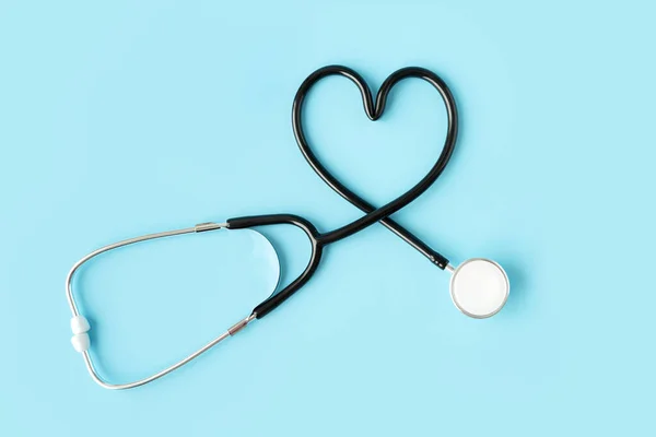 Stethoscope forming a heart on pastel blue background. Medicine and health concept.