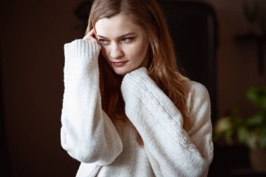 Beyaz kazaklı, genç ve güzel bir kadın ellerini yüzüne yaklaştırıyor ve şöyle düşünüyor: