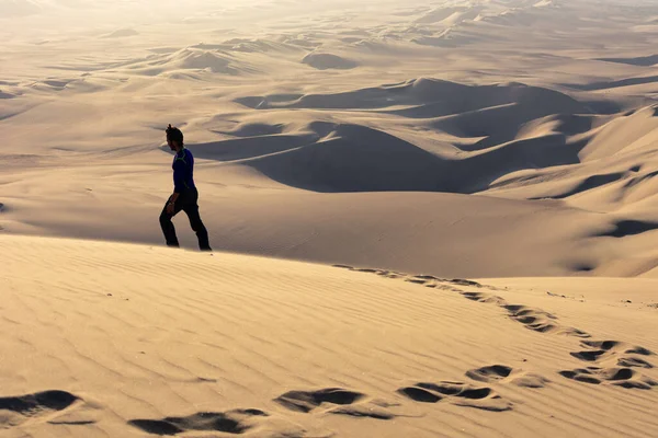 Young man in pants walking lost on the desert sand