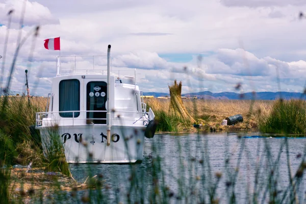 Peru 'nun güneyindeki Puno, Peru' da bulunan yüzen bir şehir olan Titicaca Gölü üzerinde Peru bayrağı olan beyaz bir tekne..