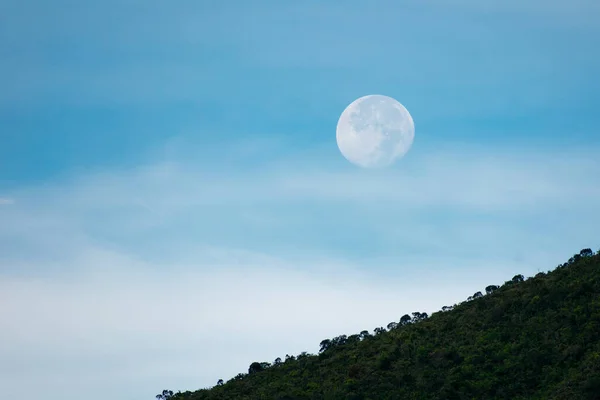 Sabah dolunay var, mavi gökyüzü ve dağda biraz bulutlu.