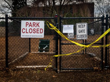 Kasabanın köpek parkı, koronavirüs ve sosyal mesafe nedeniyle kapalı. Siyah tel tel çitler, kapının karşısındaki parlak sarı uyarı bandıyla ve her kasaba için kapalı bir park ve parkın yakın olduğunu açıklayan bir başka işaretle seçildi. 