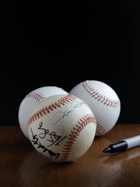 Üç beysbol topu sağda açık bir kaleciyle bir ahşap masaya dizildi. Öndeki top, 1940-1953 yılları arasında Boston Red Sox atıcısı olan Dominic DiMaggio tarafından imzalandı..