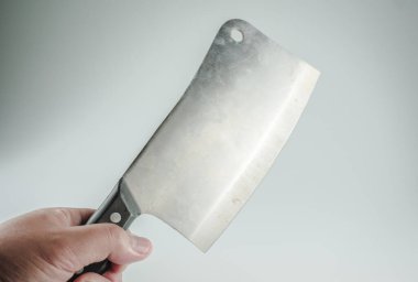 Beyaz arka planı olan bir kasap bıçağını tutan el. Beyaz arka planda bir kasap eti. Et kesiciler ve aşçılar için önemli bir araçtır.