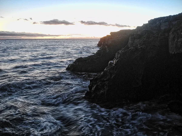 夕阳西下的岩石海岸和悠闲的海水 — 图库照片