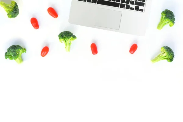 Рабочее место с брокколи, помидоры с ноутбуком — стоковое фото