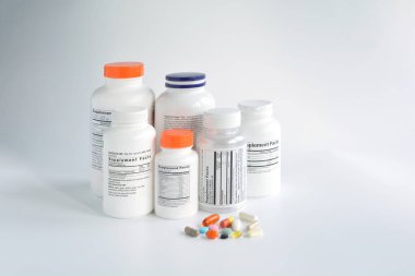 Beyaz arka planda hapları olan bir grup takviye şişesi.