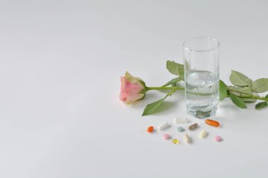 Beyaz arka planda gül olan güzellik ve sağlık için ilave haplar. Şablonlar için ilaç bileşimi, metin yeri olan posterler.