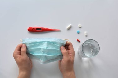 Beyaz arka planda enfeksiyon kapmasın diye tıbbi maske takan eller. Metin konumuyla şablon