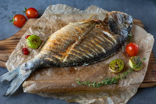 Ahşap tabakta ızgara sebzeli kızarmış dorada balığı.