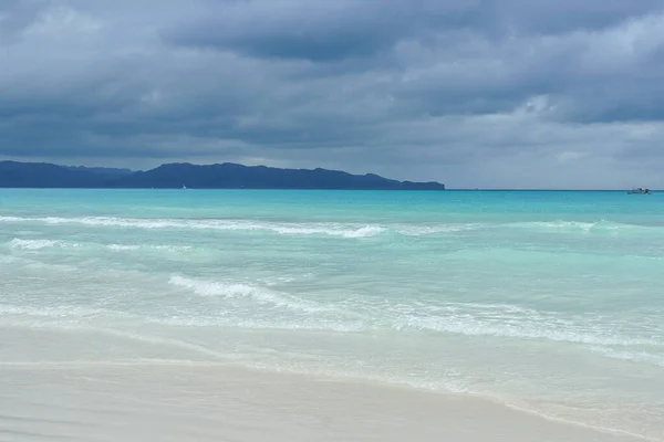 turquoise sea, white sand, dark sky after storm, mountains on the horizon. paradise tropical island, vocation concept. Boracay island, white baech, Phillipines