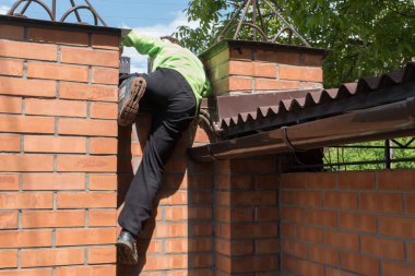 Çocuk evin dışındaki tuğla çitin üzerinden tırmanıyor. Özgürlük, çocuk merakı, itaatsiz çocuk ve yurdun dışındaki tehlike ve kaçırılma riski. 
