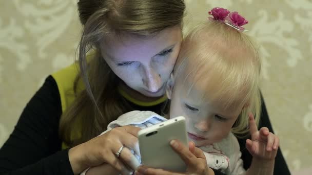Мама учит свою маленькую дочь писать сообщение на смартфоне — стоковое видео