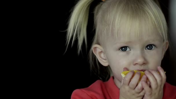 小さなブロンドの女の子を食べるオレンジのスライスの抽象的なクローズ アップ — ストック動画