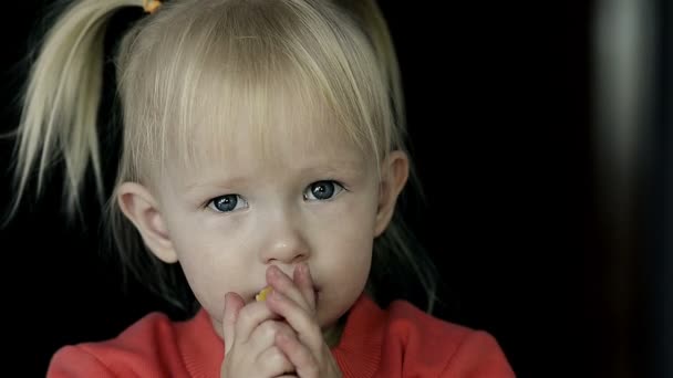 Nahaufnahme eines kleinen blonden Mädchens, das eine Scheibe Orange isst — Stockvideo
