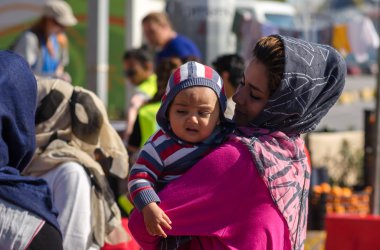 Ona anne tutan küçük silah Suriyeli mülteciler kalabalık arka plan üzerinde bebeğim