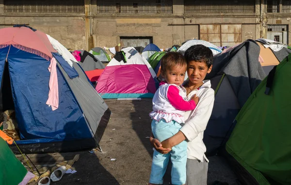 Syryjski chłopiec z siostra w ramionach w namiocie obozu dla uchodźców. Obrazy Stockowe bez tantiem