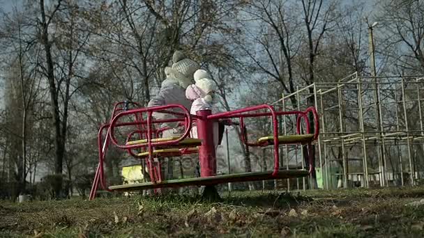 Mère avec une jeune fille chevauchant sur une balançoire dans le parc — Video