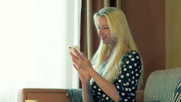 Stäng upp vackra flicka med Smartphone hemma på soffan — Stockvideo