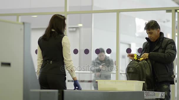 Miembro del personal del aeropuerto comprueba la mochila del pasajero y pertenencias en los artículos prohibidos — Vídeo de stock
