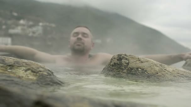Мужчина принимает горячую минеральную ванну на пляже курорта — стоковое видео