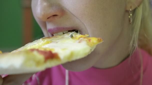 Close-up de uma menina comendo uma fatia de pizza suculenta em um restaurante — Vídeo de Stock